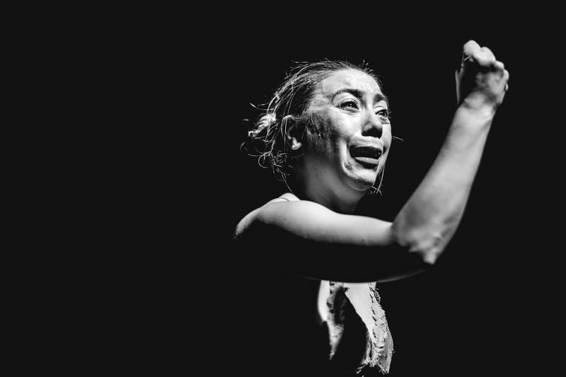 Escena de Pretexto en blanco y negro. Una actriz con el brazo en alto.